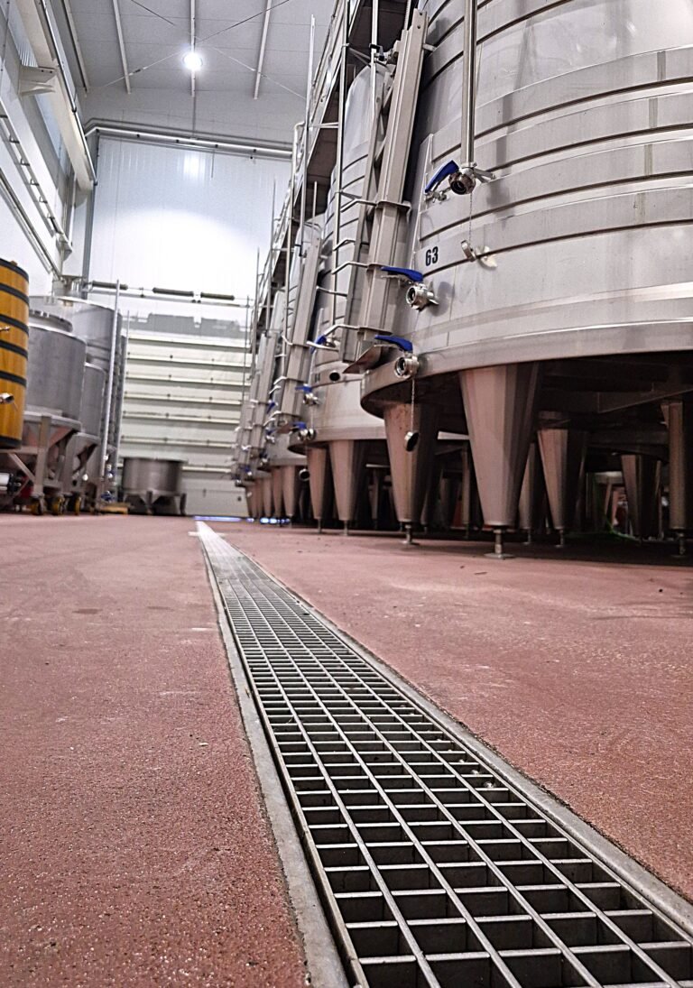 Canal de acero inoxidable con rejilla instalada en pavimento de bodega industrial INZA para drenaje de alto caudal